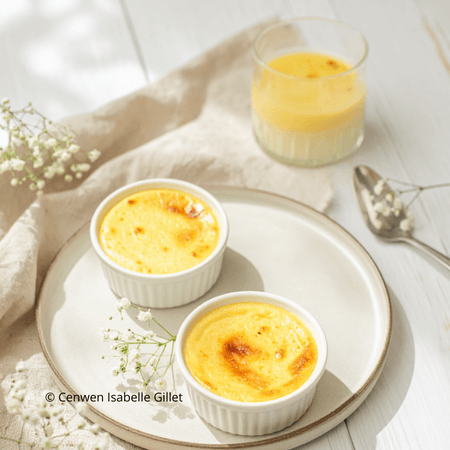 Crème prise au four, dessert maison, légèrement dorée, servie dans des ramequins sur une assiette claire avec une lumière naturelle.