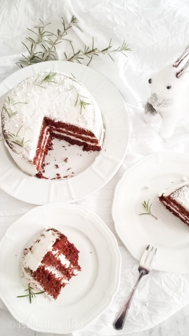 Gâteau naked cake végan décoré de romarin et sucre glace, avec une part coupée à côté.
