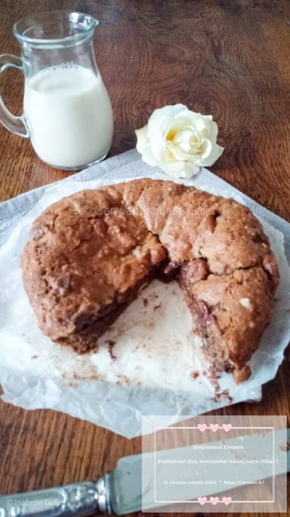 Cookie géant doré, parsemé de pépites de chocolat fondantes, présenté sur une assiette.