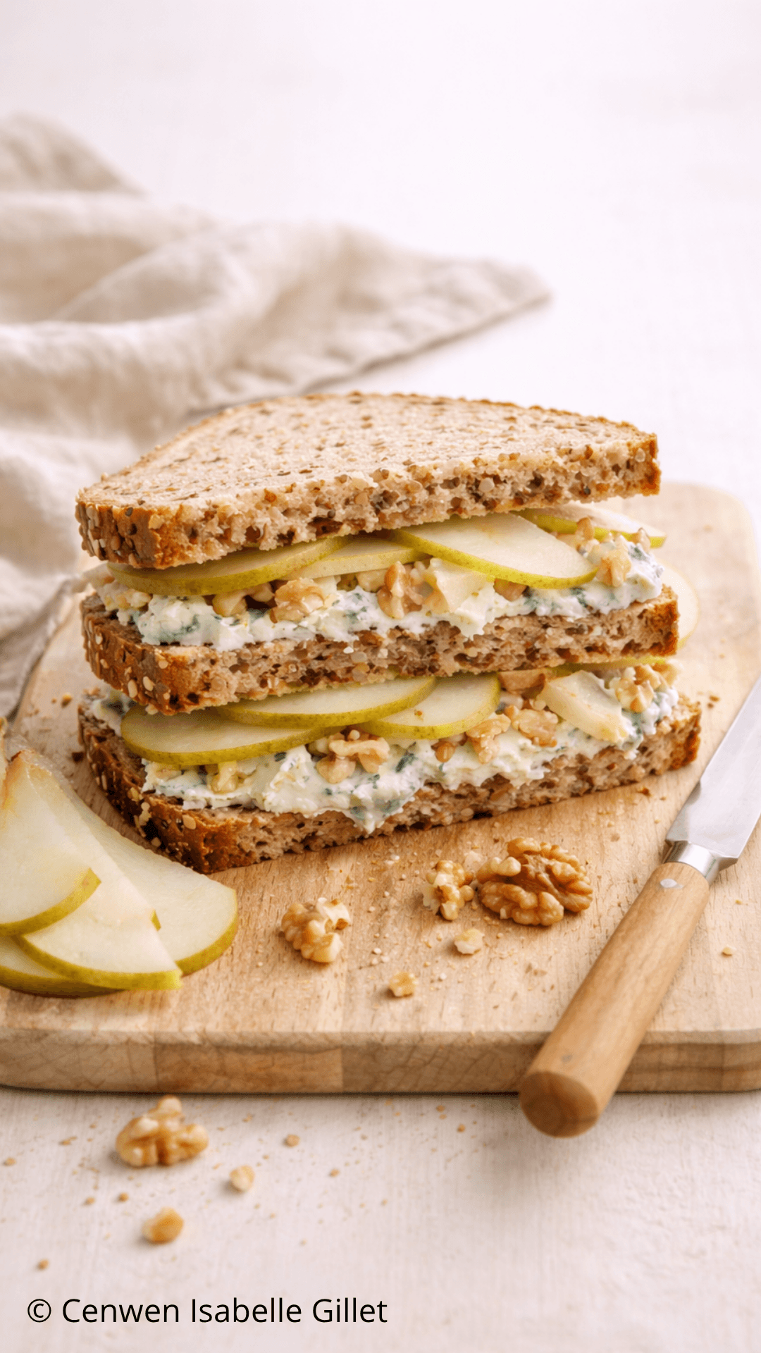 Sandwich au roquefort, poire et noix avec salade, présenté en trois tranches sur une planche.