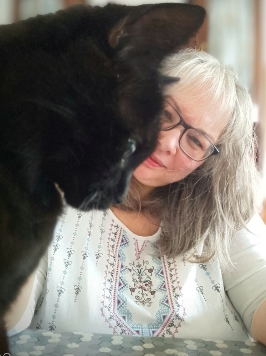 Cenwen sourit derrière son chat noir, photo officielle de l’autrice du blog culinaire et poétique Cenwen.net.