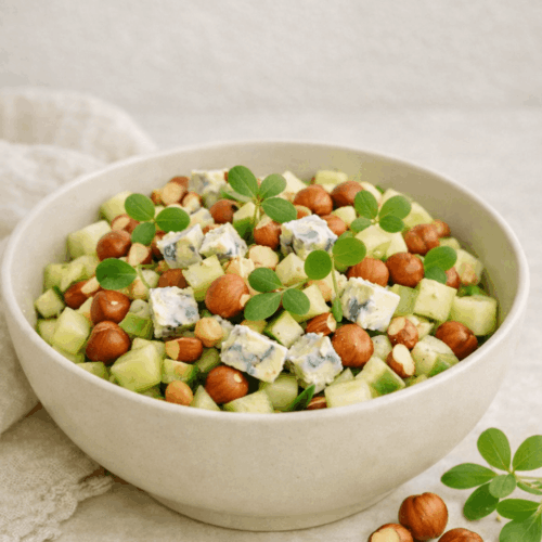 Salade de concombre au Bleu d'Auvergne, noisettes grillées et feuilles de pourpier frais servie dans un bol.
