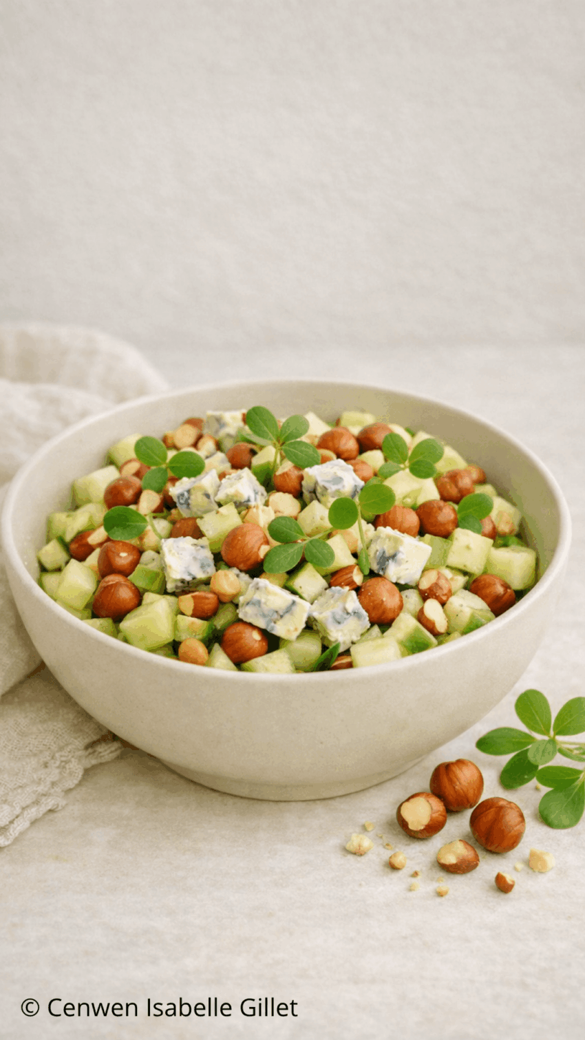Salade de concombre au Bleu d'Auvergne, noisettes grillées et feuilles de pourpier frais servie dans un bol.