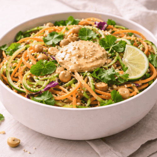 Salade de concombre et carotte à la thaïlandaise dans un bol en céramique blanc, parsemée de graines de sésame et de coriandre fraîche.