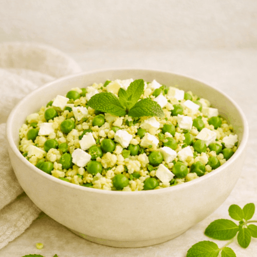 Salade de boulgour fraîche aux petits pois, feta émiettée et feuilles de menthe dans un saladier.