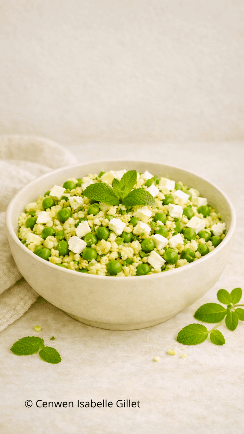 Salade de boulgour fraîche aux petits pois, feta émiettée et feuilles de menthe dans un saladier.