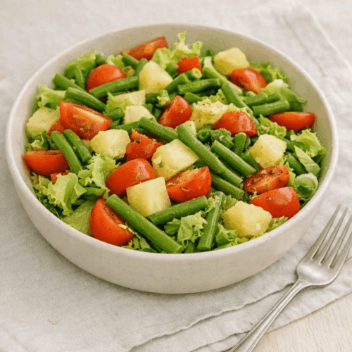 Salade tourangelle aux haricots verts, dés de pommes de terre et tomates dans un grand bol blanc.